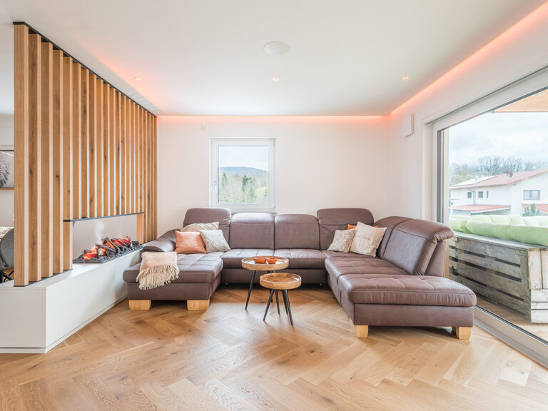 Im hellen Wohnzimmer des Chalets schafft die dunkle Couch einen passenden Kontrast.