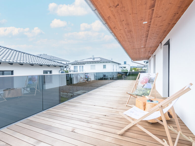 Auf der großen Terrasse des Chalets "Bayerwald Refugium" stehen zwei Holzliegestühle zum Sonnen und Entspannen.