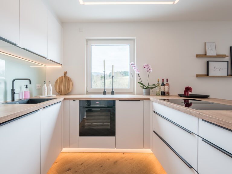 Die moderne weiße Designküche mit schwarzen Elementen des Chalets "Bayerwald Refugium".