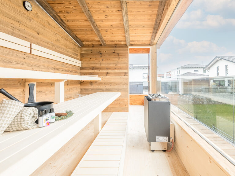 Die Panoramasauna aus Holz bietet durch das große Fenster einen Blick über die Umgebung des Bayerischen Waldes.